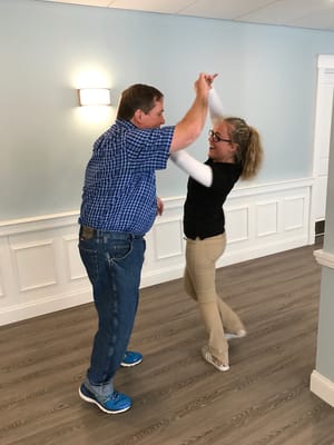 Resident and staff dancing in a facility hallway