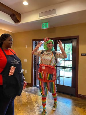 Clown entertaining residents with staff in a common area