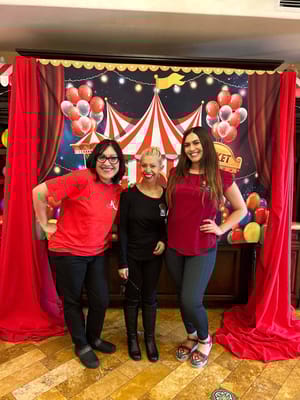 Three staff members posing in front of a festive backdrop
