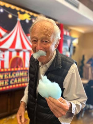 Elderly man enjoying cotton candy at a carnival-themed event