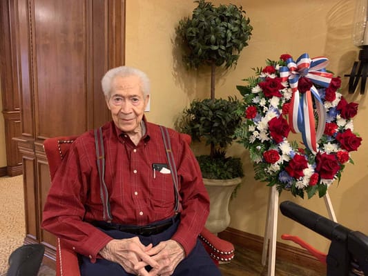 Resident seated beside a floral arrangement indoors