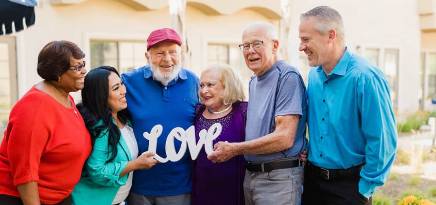 Residents and staff celebrating outdoors with a sign that says 'love'