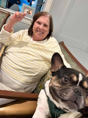 A resident smiling with a dog in a cozy setting