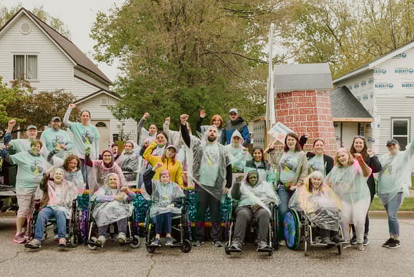 Residents and staff celebrating outdoors in colorful ponchos