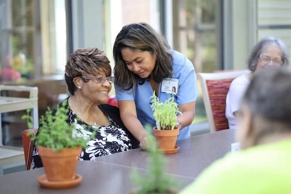 Staff member assisting resident with a plant in a common area