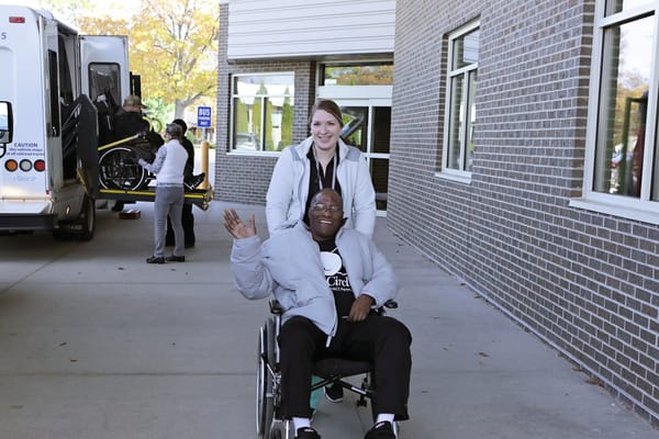 Resident in a wheelchair with staff member outside