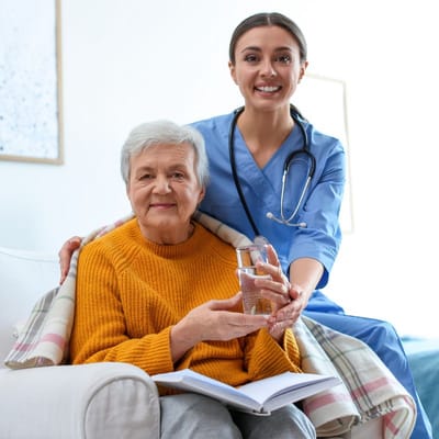A caregiver and resident posing in a warm common area