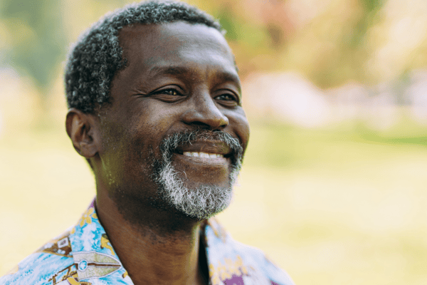 A smiling man in a colorful shirt outdoors