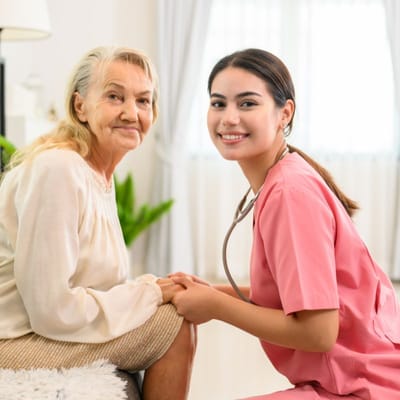 A nurse interacting with a senior resident in a bright room