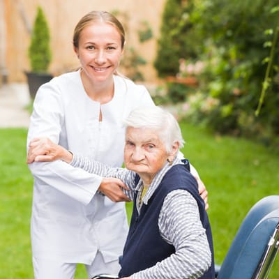 Nurse assisting elderly resident in a garden