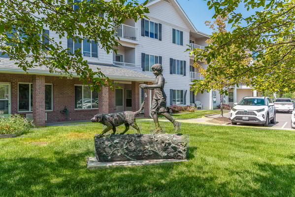 Outdoor statue of a child walking a dog near the facility