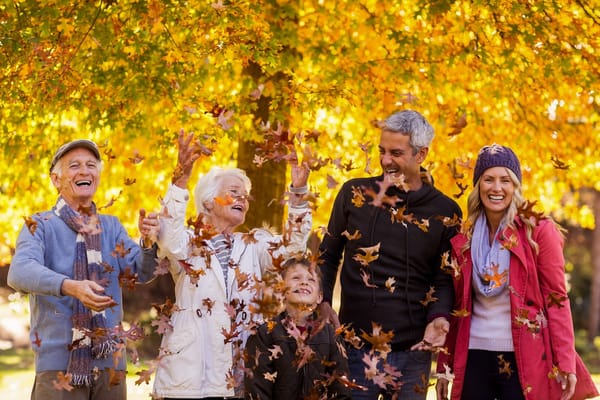 Seniors joyfully playing with leaves in a park