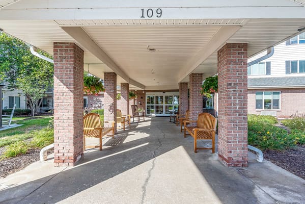 Covered entrance area with benches and landscaping