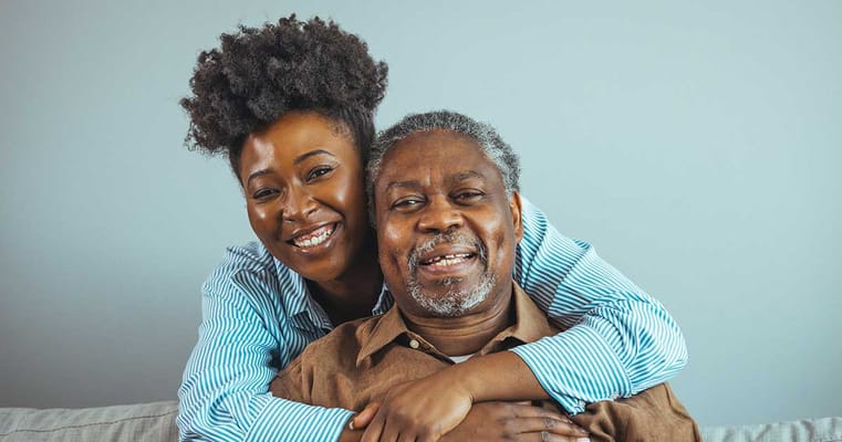 A caregiver hugging a senior man, both smiling