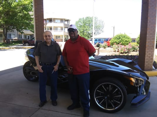 Resident and staff member posing with a vehicle outside