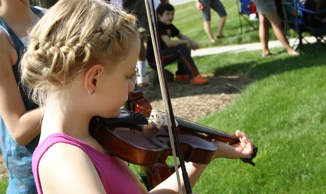 A child playing the violin at an outdoor event