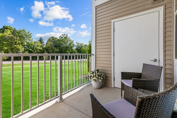 Balcony view with chairs and flowers overlooking green space