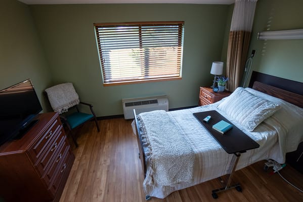 Cozy resident room with bed, TV, and window