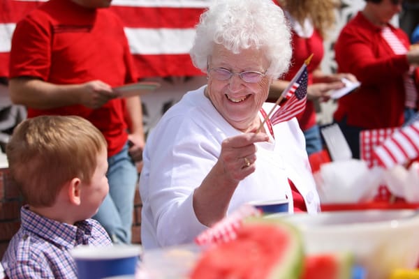 An elderly woman enjoying a celebration with a child.