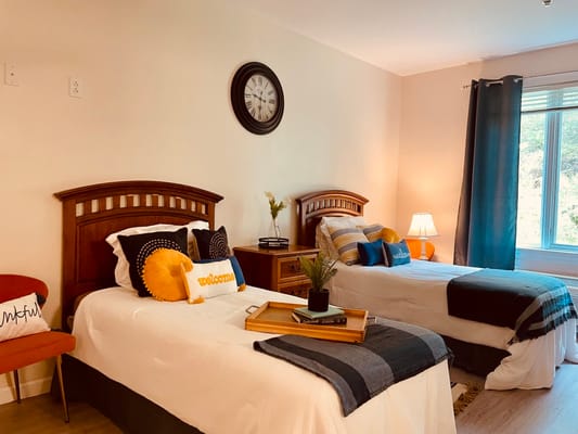 Well-decorated resident room with two beds and a clock