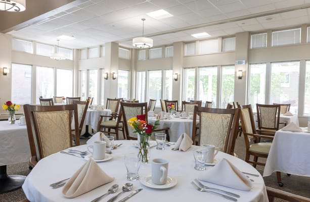 Bright dining room set for a meal with flowers on the tables