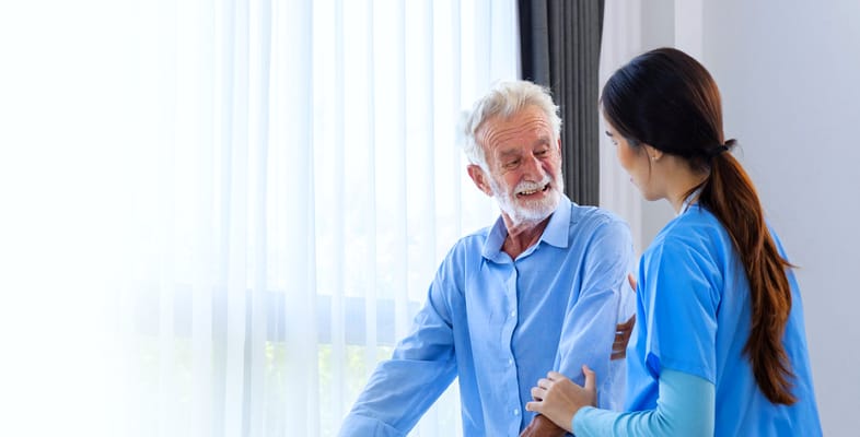 A caregiver assisting a senior man in a bright room