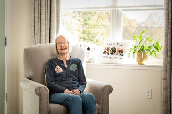 Smiling resident sitting in a cozy chair by a window
