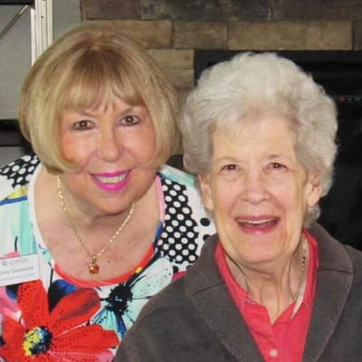 Two smiling women, one a resident and the other staff
