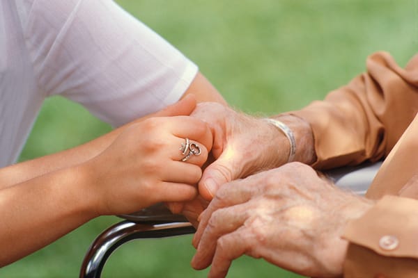 A caregiver holding the hand of an elderly resident