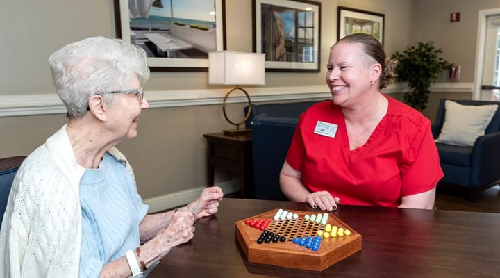 Resident and staff playing a game in a common area