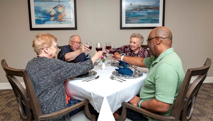 Four residents toasting at a dining table