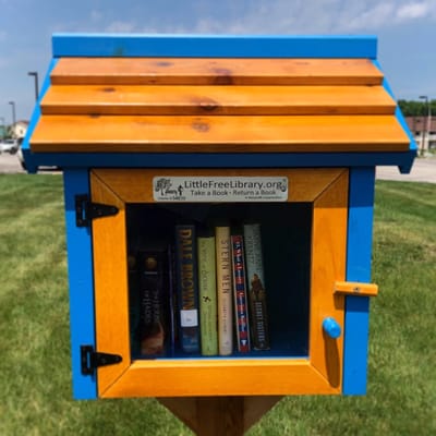 A colorful Little Free Library in a grassy area