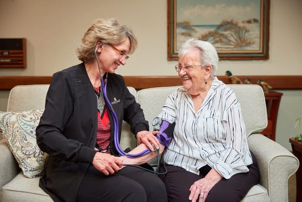 Staff member taking a resident's blood pressure with a smile