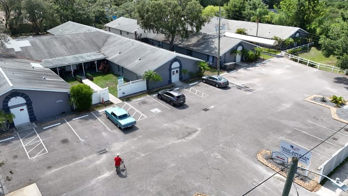 View of the parking lot at Great American Assisted Living with an elderly resident walking