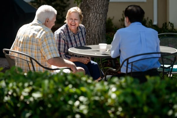 Three residents enjoying conversation at an outdoor table