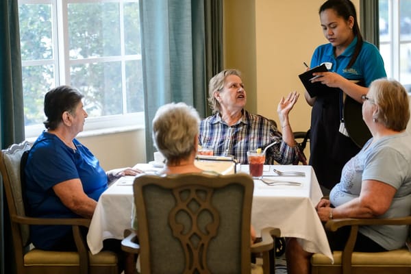 Residents and staff interacting at a dining table