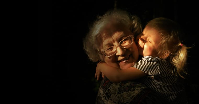 An elderly woman shares a heartfelt hug with a young child