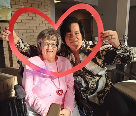 Residents celebrating with a heart-shaped frame in a common area