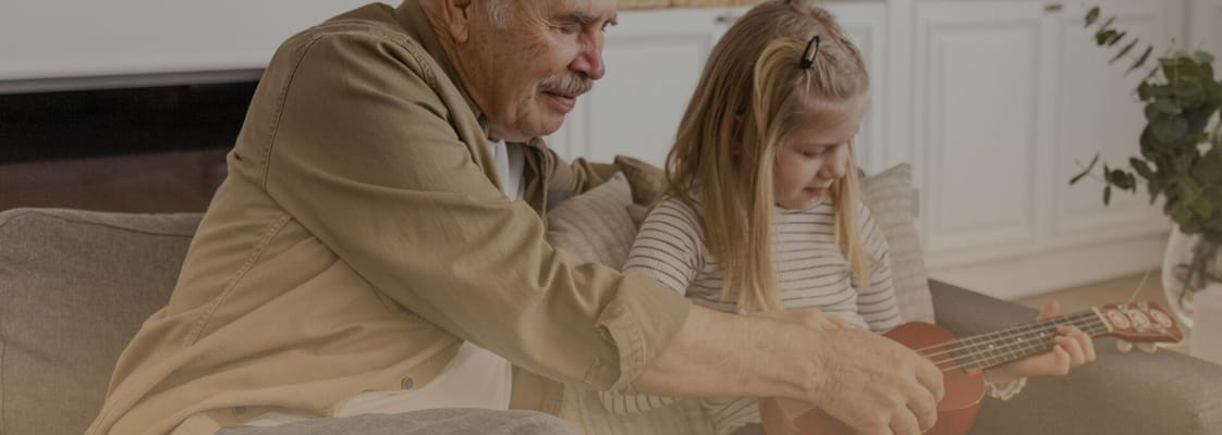 Senior man and girl playing a ukulele together