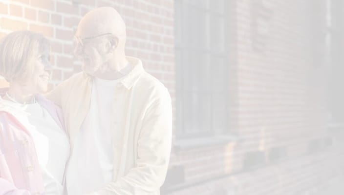 A couple smiling together near a brick building