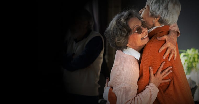 Two residents embracing warmly in a social setting