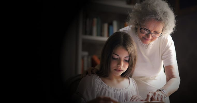 An elderly woman assisting a young girl with a book