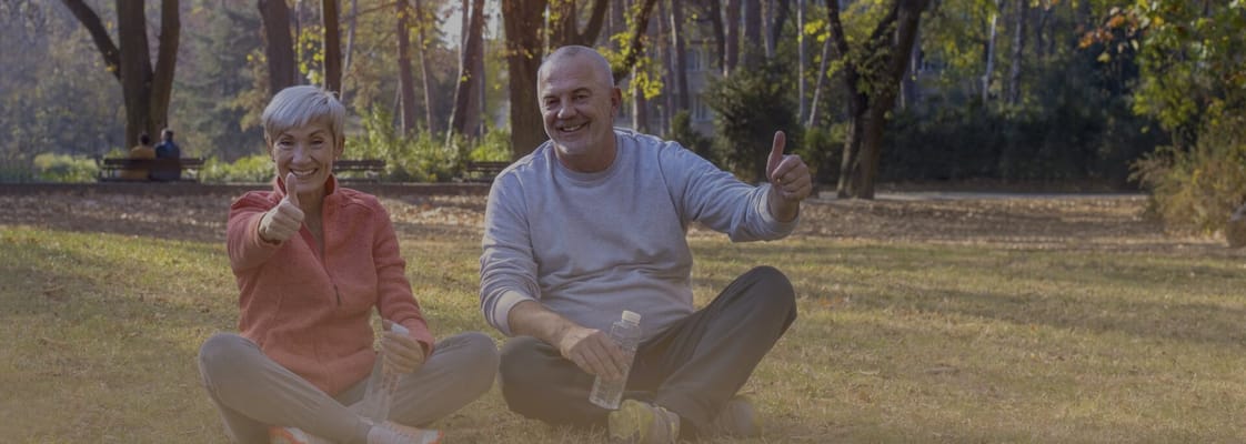 Two seniors sitting together in a park, smiling.