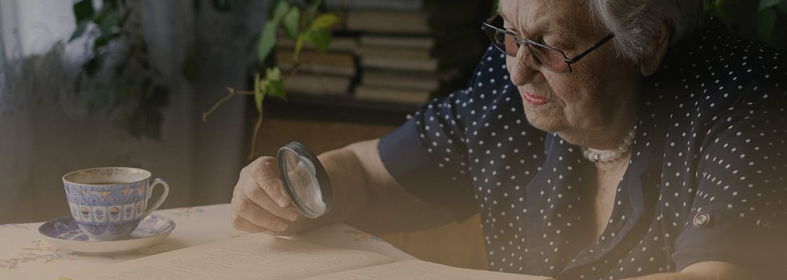An elderly woman reading a book by a window