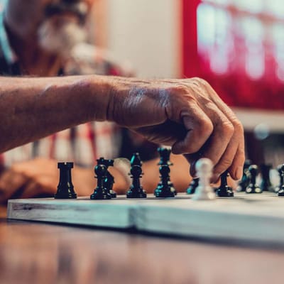 Close-up of a resident playing chess with a hand visible