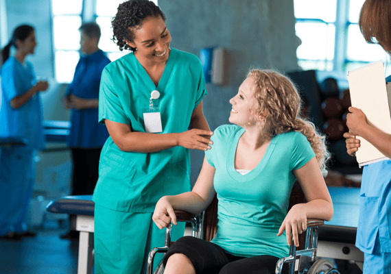 Staff assisting a young woman in a wheelchair