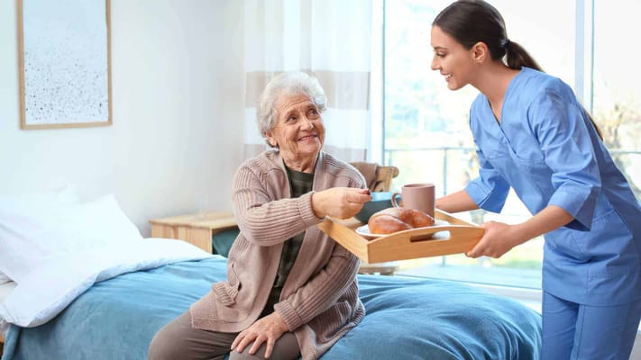 Caregiver serving food to resident in a cozy interior room