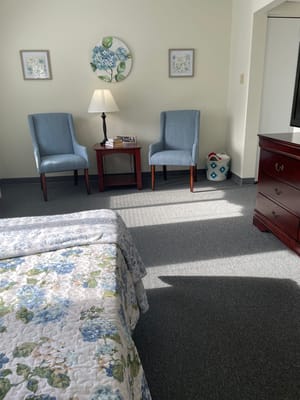 Cozy resident room with two chairs and a bedside table