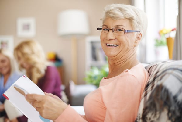 Resident smiling while reading in a cozy common area