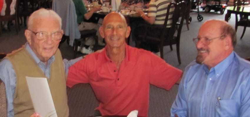 Three residents smiling in a dining room setting